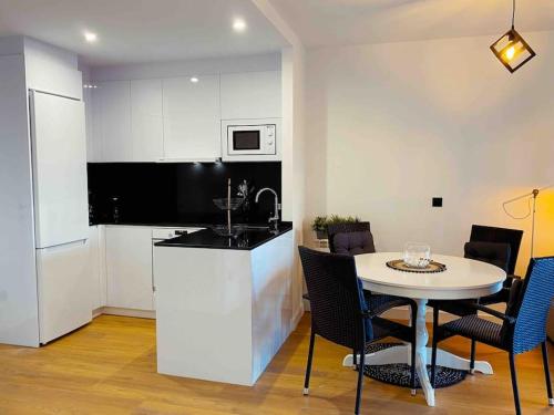 eine Küche mit einem Tisch und eine kleine Küche mit einem Tisch und Stühlen in der Unterkunft Apartamento en Edificio Nuevo con Piscina in Portonovo