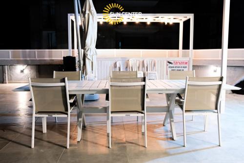 Sun Center Eilat في إيلات: طاولة طعام بيضاء وكراسي في مطعم