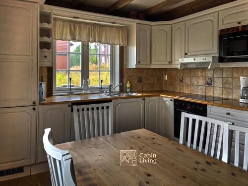 a kitchen with white cabinets and a wooden table at Nice apartment in Trysil ski in-out, sauna and view in Trysil