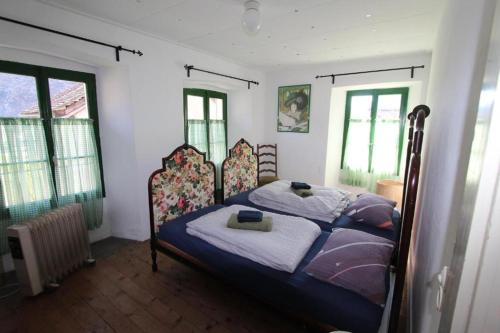 a bedroom with a bed and two windows at Camera in Casa Eva in Brione