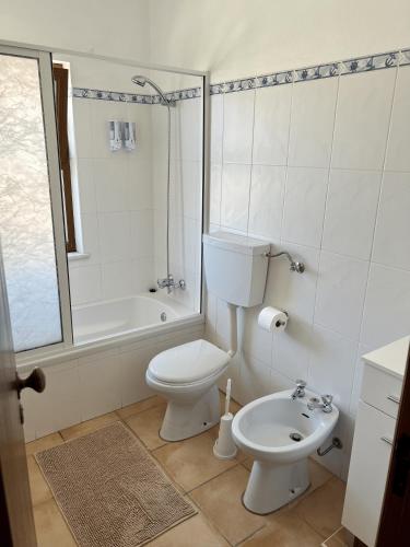 a bathroom with a toilet and a tub and a sink at Apartamentos Guiomar Campos in Porto Covo