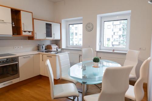 cocina con mesa de cristal y sillas blancas en Suzana Iron's apartment, en Liubliana