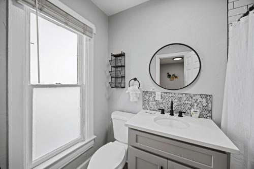 a white bathroom with a sink and a mirror at Charming Vintage Cottage with Hot Tub & Free Bikes! in Fort Collins