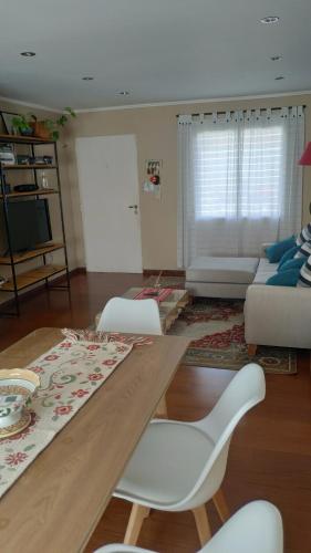 a living room with a wooden table and white chairs at Lo de Lucas in Olavarría
