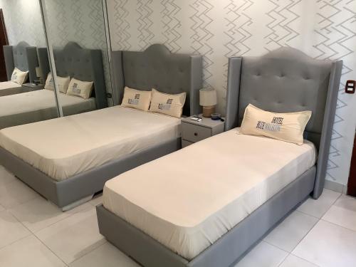 Duas camas individuais num quarto com um espelho. em Hotel Blue Malecón And Spa em Santo Domingo