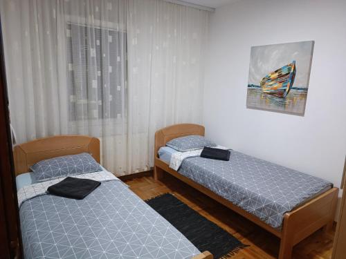 2 Einzelbetten in einem Zimmer mit Fenster in der Unterkunft Serbian home with garden in Krnjača