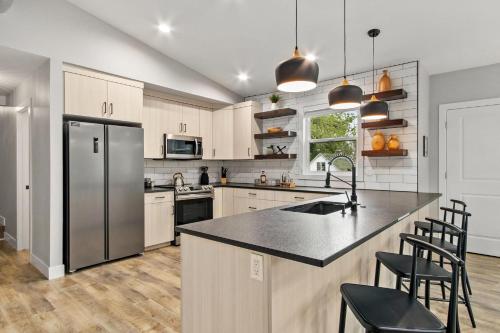 a kitchen with white cabinets and a stainless steel refrigerator at Spacious Downtown Apartment - Walk to Old Town FC! in Fort Collins
