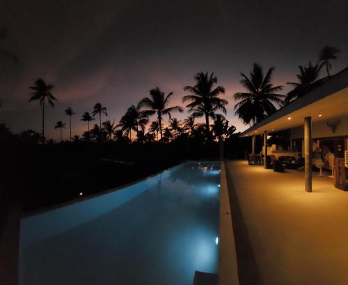 a night view of a swimming pool with palm trees at ORCHID LODGE SAMUI - Bed & Breakfast in Lamai