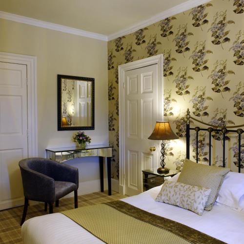 a bedroom with a bed and a chair and a desk at Washingborough Hall Hotel in Lincoln