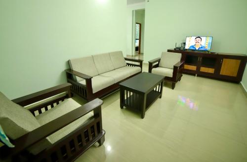 a living room with a couch and a tv at TrueLife Comfort Inn - Near PS4 veg restaurant - On way to Balaji Temple - 2BHK AC apartments - Coffee Tea Milk - Fast WiFi, Kitchen, Dining, Android TV, Parking - Easy access to Airport, Railway Station and to all Temples - Top service with lots of Love in Tirupati