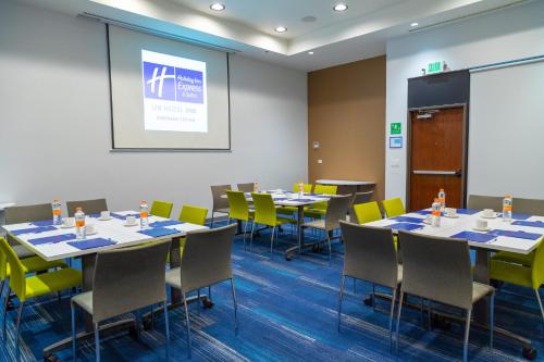 a conference room with tables and chairs and a screen at Holiday Inn Express & Suites - Ensenada Centro by IHG in Ensenada