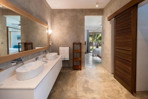 a bathroom with two sinks and a large mirror at Koki Bonheur by muse villas in Poste Lafayette