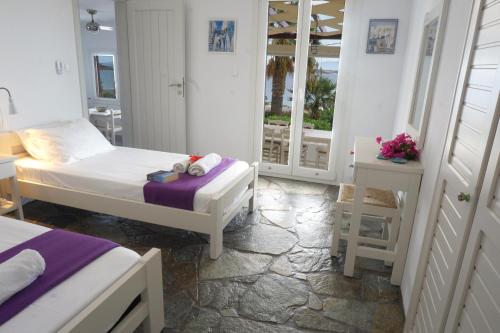 1 dormitorio con 2 camas y una mesa con flores en Playera Bungalow G sea view, en Naousa