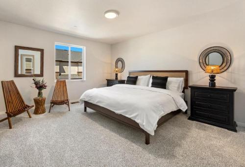 a bedroom with a bed and two chairs and a mirror at Modern Farmhouse Townhome - Great Central Location in Fort Collins