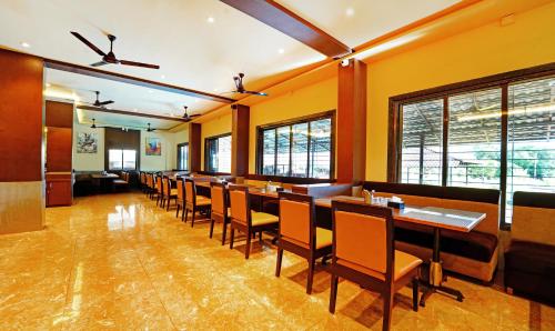a restaurant with a long row of tables and chairs at Treebo SS Residency With Mountain View in Dapoli