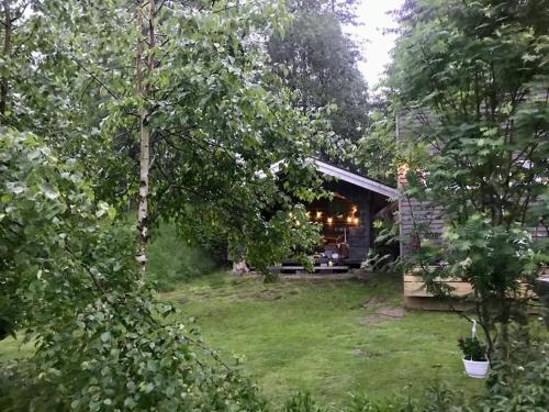 a cabin in the middle of a yard with trees at 15 min från Ullared! Ny stuga med hög standard! in Älvsered