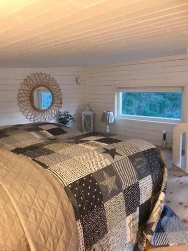 a bedroom with a bed and a mirror and a window at 15 min från Ullared! Ny stuga med hög standard! in Älvsered