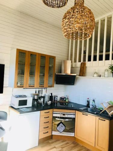 a kitchen with wooden cabinets and a black counter top at 15 min från Ullared! Ny stuga med hög standard! in Älvsered