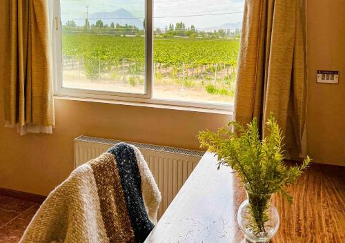 a room with a table and a window with a vineyard at Hotel El Almendro in Paine