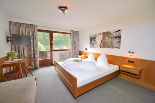 ザンクト・アントン・アム・アールベルクにあるHotel Garni Bergweltの大きなベッドとデスクが備わるホテルルームです。