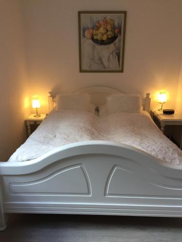 a white bed in a bedroom with two lamps at Fischerstuuv in Husum