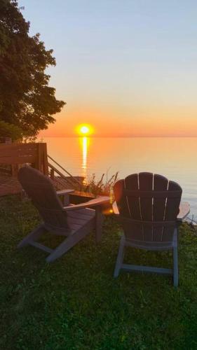 two chairs sitting in the grass watching the sunset at Lakefront Cottage w/ Private Beach- Niagara 