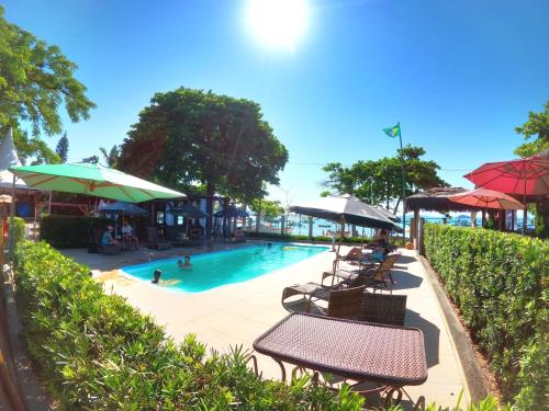 una piscina con bancos y sombrillas y una piscina en Hotel Pé na Areia, en Penha