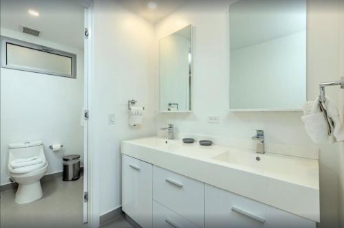 a white bathroom with a sink and a toilet at Breath Taking Beach Front Views Condo Eagle Beach in Palm-Eagle Beach