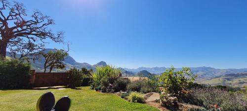 a person standing in a yard with a view of mountains at Chales Canto da Natureza in São Bento do Sapucaí