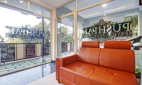 an orange leather couch in a room with windows at Treebo Pushpak Service Apartment in Cochin