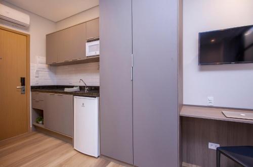 a kitchen with white cabinets and a tv on the wall at GoÁtica Aeroporto Congonhas in Sao Paulo