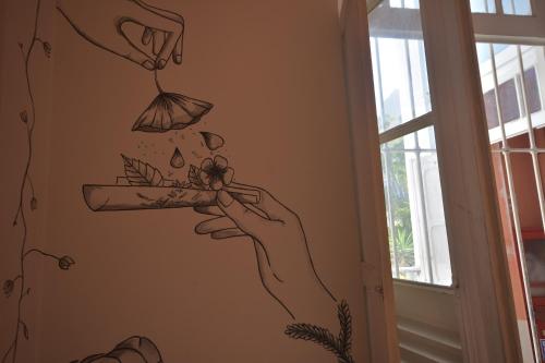 a drawing of a hand holding a flower on a wall at Aurora Hostel Rio in Rio de Janeiro