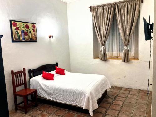 a bedroom with a bed with red pillows and a window at Hotel Casa Blanca in El Oro de Hidalgo