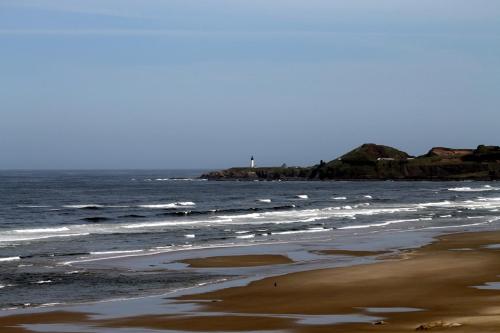 a beach with the ocean and rocks in the background at Inn at Nye Beach in Newport