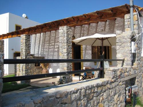 ein Steinhaus mit einem Regenschirm und einem Tisch in der Unterkunft Tilos Fantasy in Livadia