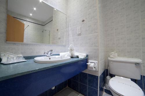 a bathroom with a toilet and a sink and a mirror at Bella Vista Hotel in St Paul's Bay