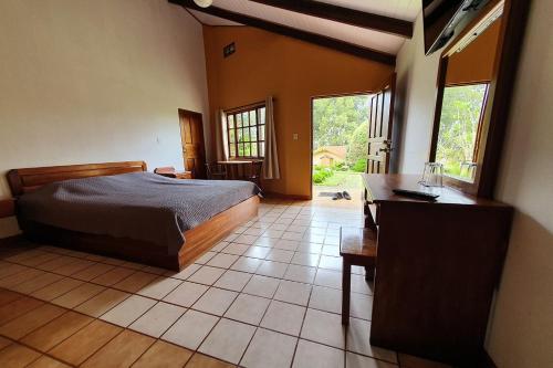 a bedroom with a bed and a desk and window at Hotel Villa Zurqui in San José