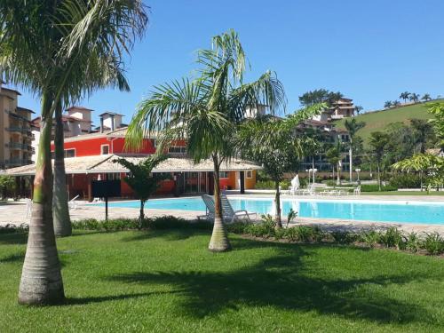 un complejo con piscina y palmeras en Apartamento a 50m da areia - Praia da Tabatinga en Caraguatatuba