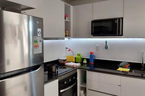 una cocina con armarios blancos y un aparato de acero inoxidable en Hermoso conjunto residencial con piscina, en Asunción