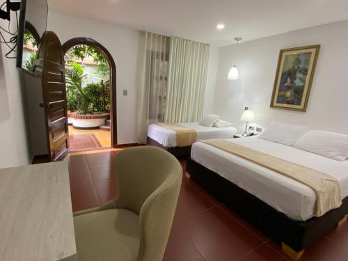 una habitación de hotel con 2 camas y una silla en Hotel Casa Colonial, en Barranquilla