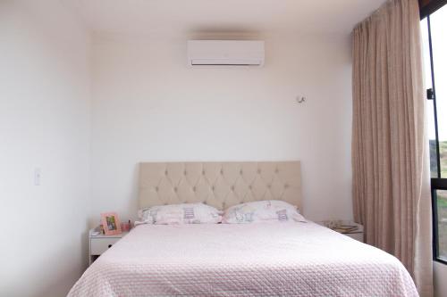 蒙蒂達斯加梅萊拉斯的住宿－Lá na Roça - Belezas do Monte Chalé, Suítes & Restaurante，卧室配有一张带白色棉被的床和窗户。