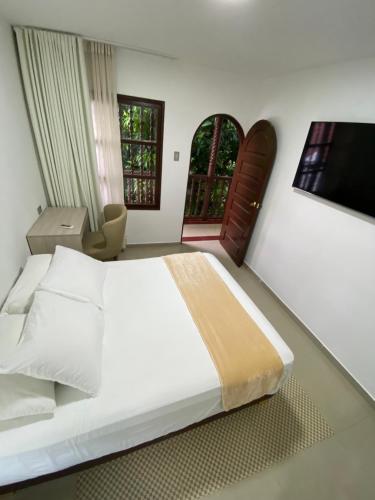 a bedroom with a large white bed and a television at Hotel Casa Colonial in Barranquilla