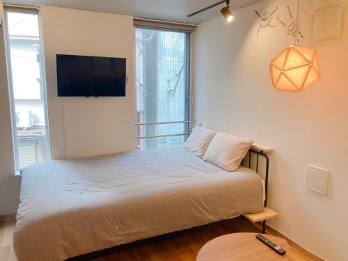a bedroom with a bed with a flat screen tv on the wall at The Aoca Tokyo Sanno in Tokyo