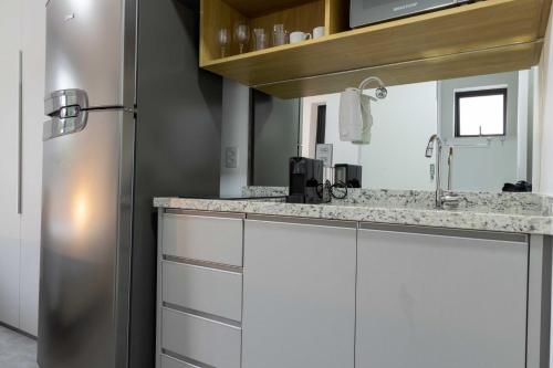 a kitchen with white cabinets and a stainless steel refrigerator at 360 Suítes Vila Mariana - Apartamentos mobiliados in Sao Paulo