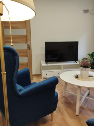 a living room with a blue chair and a table at Havel Apartment in Opole
