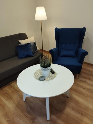a living room with a white coffee table and a blue couch at Havel Apartment in Opole