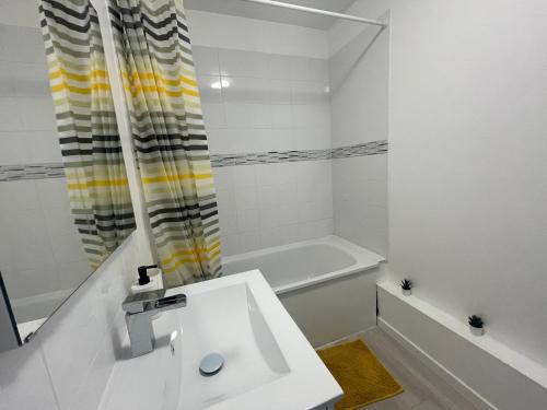 a white bathroom with a sink and a tub at Appartement Charmant Cocon Plus in Croix