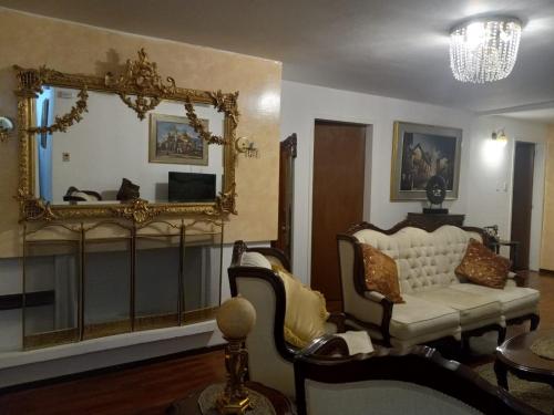 sala de estar con espejo y sofá en Elegante departamento, lavadora, sauna, jacuzzi, en Quito