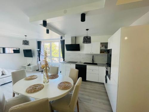 une cuisine et une salle à manger avec une table et des chaises blanches dans l'établissement Appartement Charmant Cocon Plus, à Croix