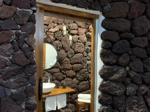baño con pared de piedra con lavabo y espejo en Las Villas de Gardel, en Icod de los Vinos